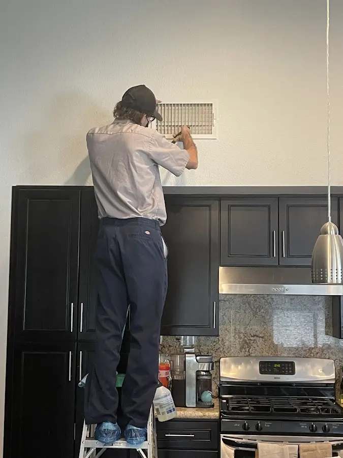 Technician inspecting an air vent during HVAC service in Valley Center